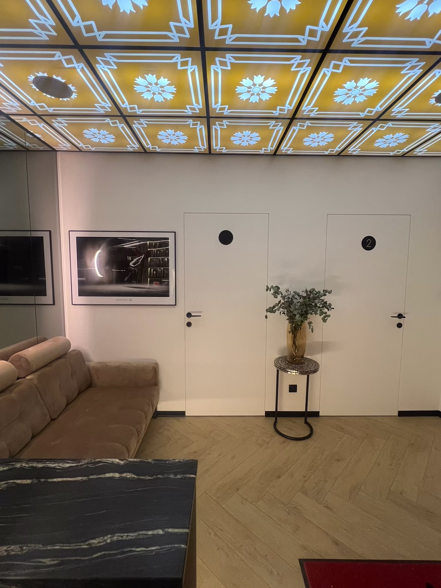 Elegancka poczekalnia w gabinecie Malendowska Aesthetic w Poznaniu. Nowoczesne wnętrze, strefa relaksu dla pacjentów i wejście do gabinetów zabiegowych.